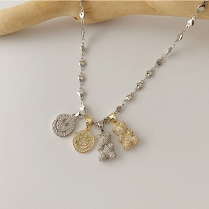 Detailed shot of teddy bear and smiley face charms on a heart link chain necklace