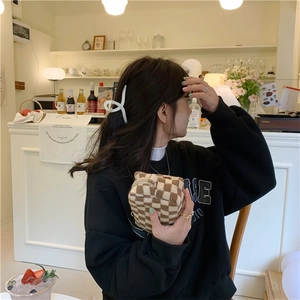 Detail showing knitted checkerboard cosmetic bag and cream matte hair claw clip