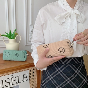 Detail of vintage corduroy makeup bags with embroidered smiles and metal zippers