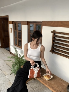 Hand-woven tote bag with orange and white diamond pattern held by model in outdoor setting