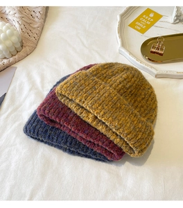 Close-up of mixed-color knit beanies in yellow, red, and navy with warm textured weave