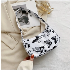 Detail of white baguette bag featuring delicate black butterfly prints and zipper