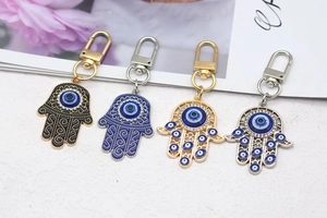 Detail of Hamsa Hand and Evil Eye keychains in gold and silver metal with enamel finish