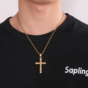 Close-up of gold twist chain necklace with textured cross pendant worn by male model