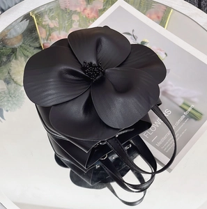 Top view of a black leather bucket bag with a large 3D leather flower and petal details