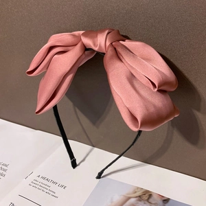 Gros plan d'un serre-tête en satin rose avec éclat soyeux sur un bandeau fin noir