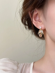 Détail de boucles d'oreilles grappes en résine dorée avec perles sur le modèle