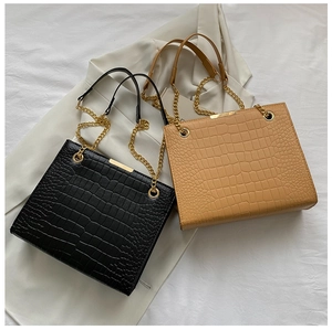 Detail of crocodile embossed leather bags in black and tan with gold chain straps