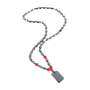 Polished black hematite beaded necklace with red bead accent and metal tag on white background