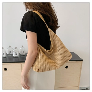 Model wearing a large handmade straw tote bag made of natural woven fabric for summer