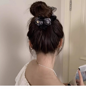Close-up of a sophisticated black lace flower hair claw clip worn by a model in a bun