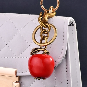 Creative red apple keychain pendant with bronze lobster clasp on a quilted handbag