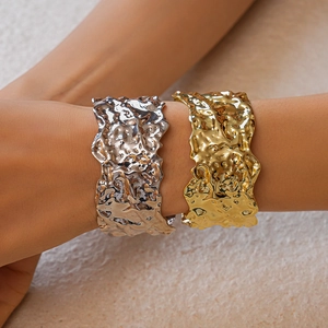 Detail of metallic textured wide cuffs in gold and silver showing the pleated design