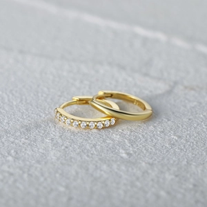 Close-up of S925 sterling silver gold earrings with wave pattern and cubic zirconia