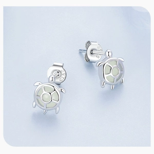 Macro view of S925 sterling silver sea turtle stud earrings with glowing stone insets