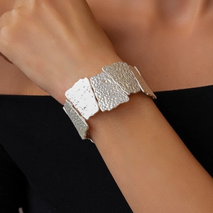 Detailed view of hammered matte silver bracelet with irregular geometric flower patterns