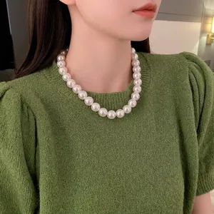 Collier de perles vintage français porté avec un pull vert pour un look chic minimaliste