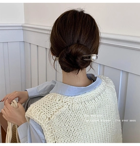 Close-up of elegant U-shaped silver hair pin with a large pearl for bun hairstyles