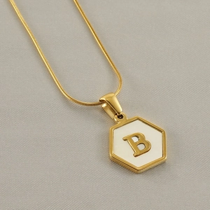 Detail of 18k gold plated hexagonal pendant with white enamel and letter B on snake chain