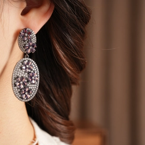Close-up of vintage oval earrings with purple floral gems and pave-set zircons