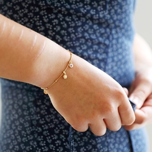 Detailed view of a gold chain bracelet featuring star pendants with purple cubic zirconia