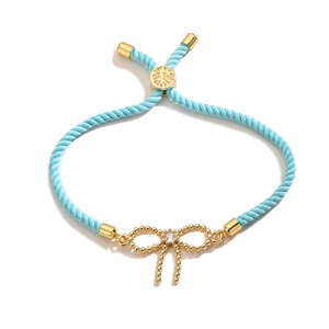 Light blue braided bracelet with a 18K gold bow charm and zircon gemstone
