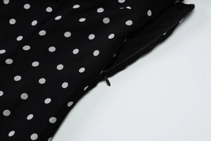 Detailed view of the invisible side zipper on a black and white polka dot summer dress
