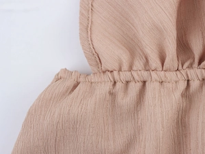 Vue macro du tissu plissé texturé rose clair montrant les détails de couture fins