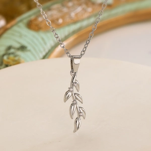 Elegant silver olive leaf pendant necklace with zircon crystals on marble background