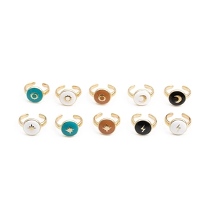Close-up of gold-plated open rings with sun moon stars lightning motifs in colorful oil drip