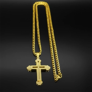 Détail d'un pendentif croix doré à double couche avec une chaîne gourmette classique en or