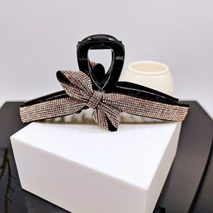 Detail of elegant black shark clip featuring a rose gold rhinestone bow decoration