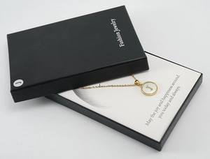 Vue détaillée du collier doré lettre J dans sa boîte cadeau noire avec carte