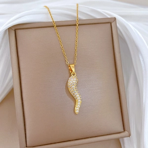 Macro detail of a gold crystal-encrusted chili pendant on a luxury jewelry box