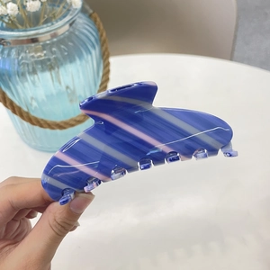Detail of large acetate hair claw clip featuring blue and lilac gradient stripes