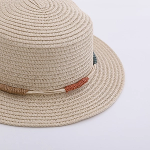 Close-up of beige straw hat with intricate weave and colorful woven rope trim detail