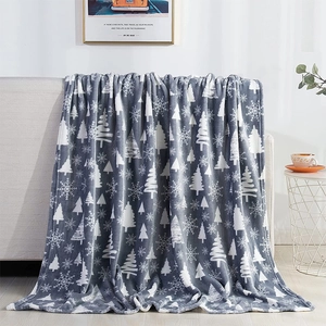 Detail of soft gray flannel blanket with white Christmas tree and snowflake patterns on a sofa