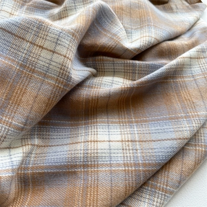 Close-up of soft plaid scarf fabric with beige, light blue and white woven texture