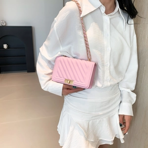 Detailed close-up of pink quilted crossbody bag with gold chain strap and turn-lock