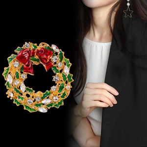 Christmas wreath brooch with green enamel leaves, red bow, and sparkling crystals