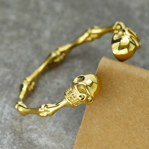 Close-up of golden skull head detail on punk style stainless steel bracelet on a rustic surface