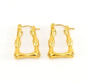 Detail of bamboo-textured gold U-shaped earrings with polished metallic finish