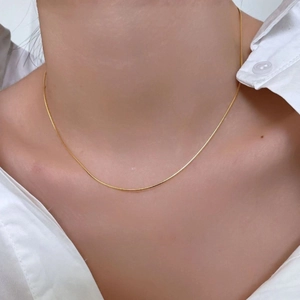 Minimalist gold snake bone chain necklace in titanium steel on a female model