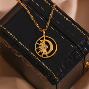 Detail of 18K gold-plated sun and moon necklace with central zircon on a jewelry box
