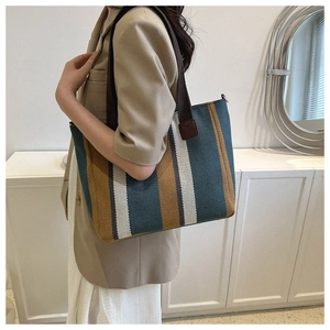 Detailed shot of striped canvas tote bag in blue and ochre with brown woven shoulder strap
