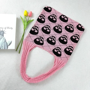 Detailed close-up of pink and black knit tote bag with festive skull jacquard pattern