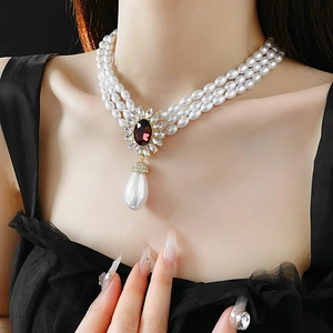 Close-up of triple-layer pearl necklace with ruby floral pendant and teardrop pearl drop