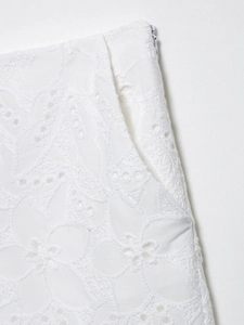 Dettaglio del ricamo bianco traforato e della cerniera invisibile sul lato del pantalone