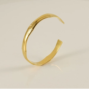 Detailed close-up of 18K gold bamboo style C-shaped open bracelet with leaf texture