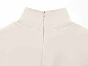 Detail view of the hidden back zipper and fine knit texture on beige high-neck top